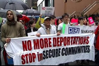 Protesters with sign reading "No more deportations, stop insecure communities"