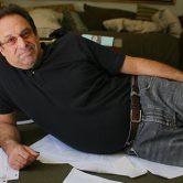 David Milch reclining amongst papers