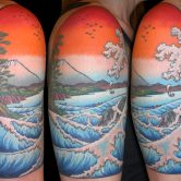 Colorful upper arm tattoos in Japanese print style with Mt. Fuji and crashing waves