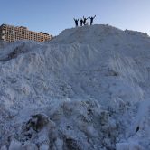 Students standing atop giant snow pile on west campus