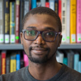 Photograph of Abdullahi Tsanni in front of shelves of books